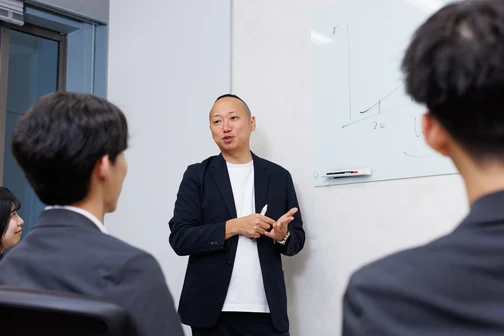 ホワイトボードの前で説明する社員